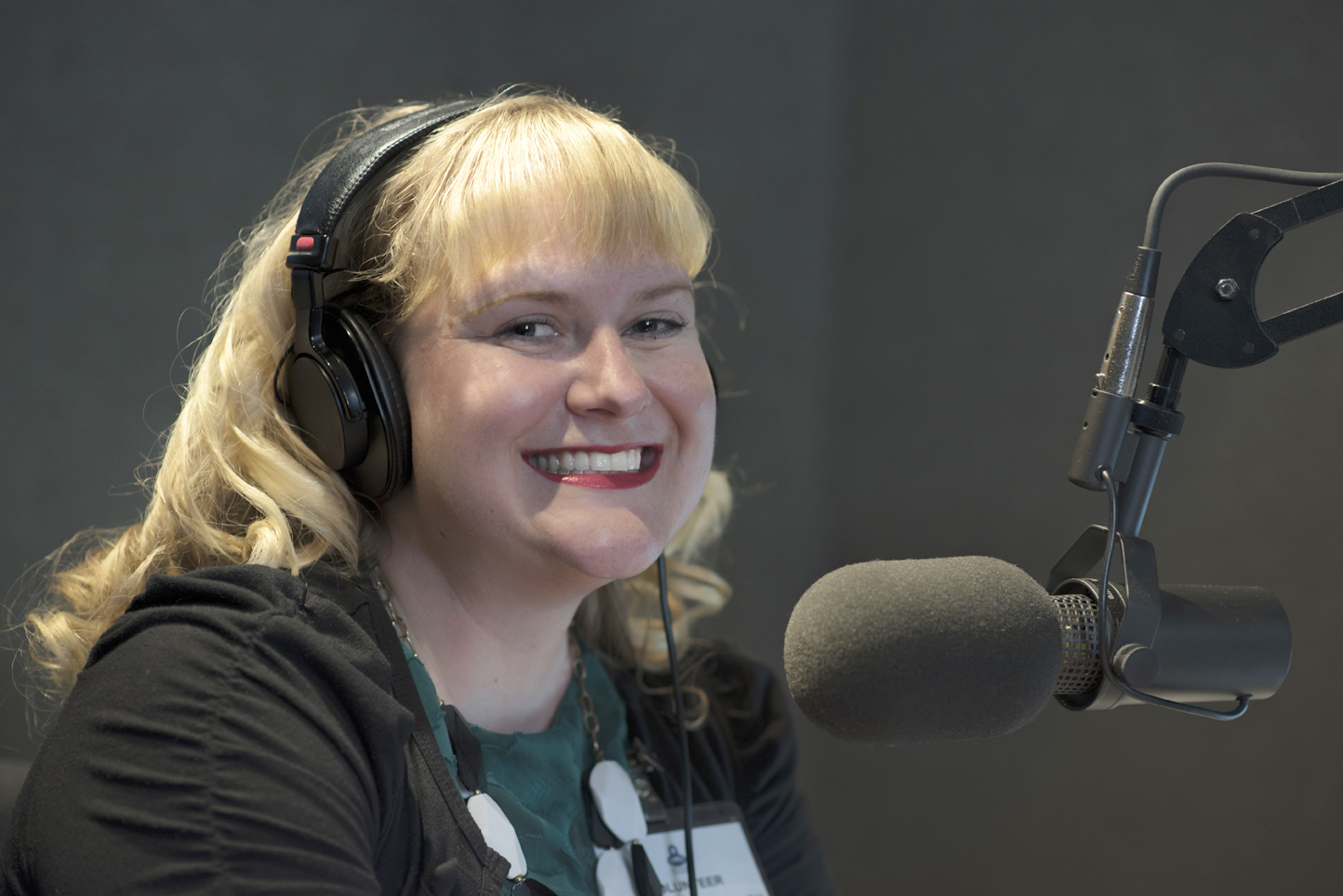 female volunteer with headphones in front of a mic 